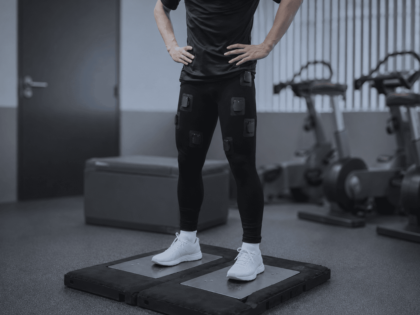 Athlete wearing the Skinetix sensor-integrated leggings performing a jump test on dual force plates in a performance gym.