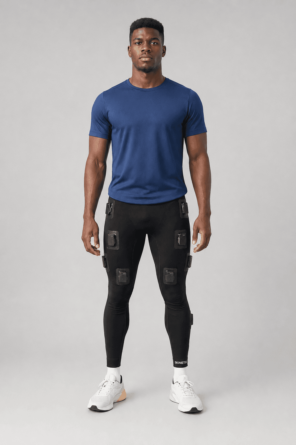 Athlete wearing the Skinetix sensor-integrated leggings in a studio setting, showing sensor module placements on the lower body.